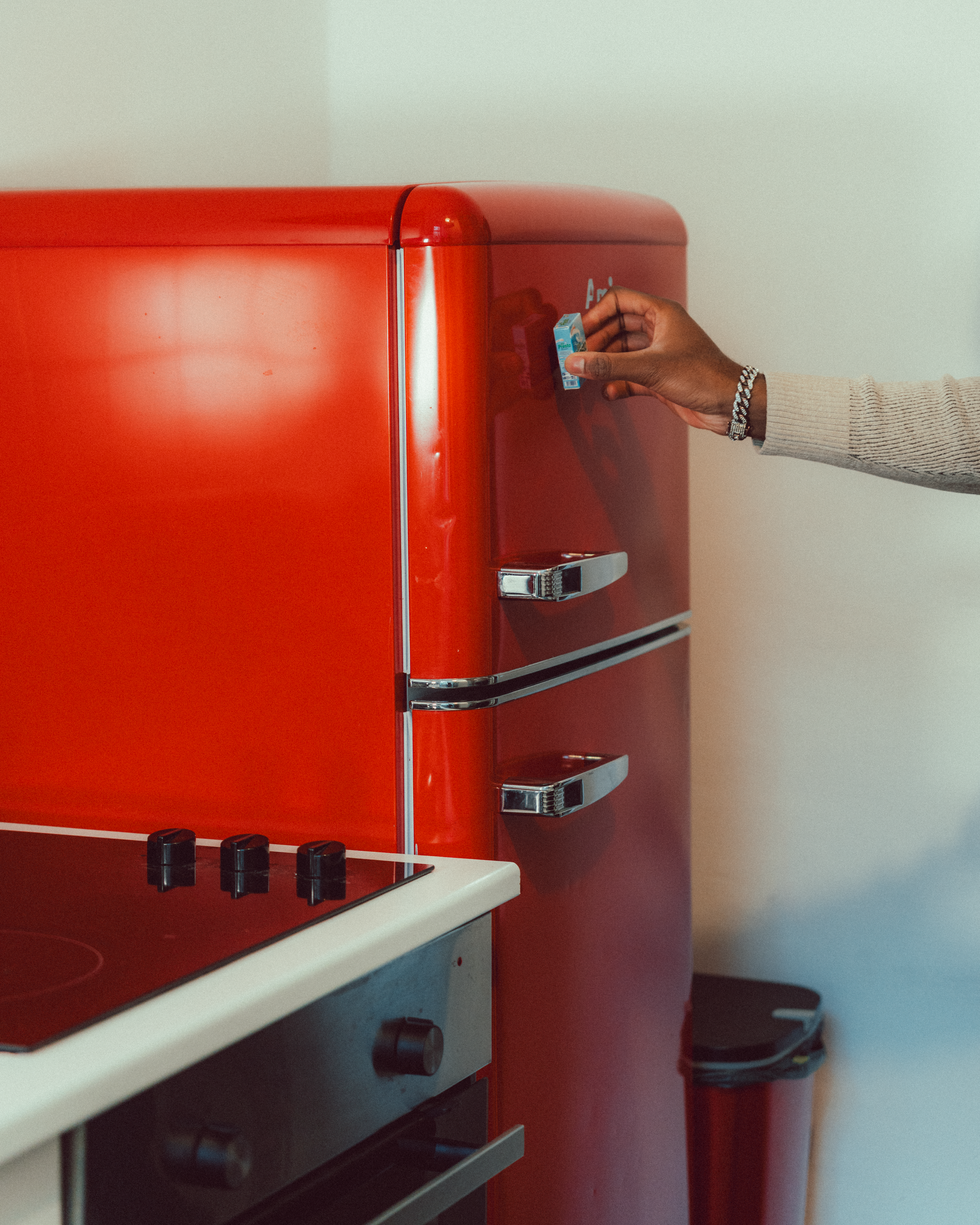An arm extends to open a vintage-style red refrigerator, creating a nostalgic kitchen scene.